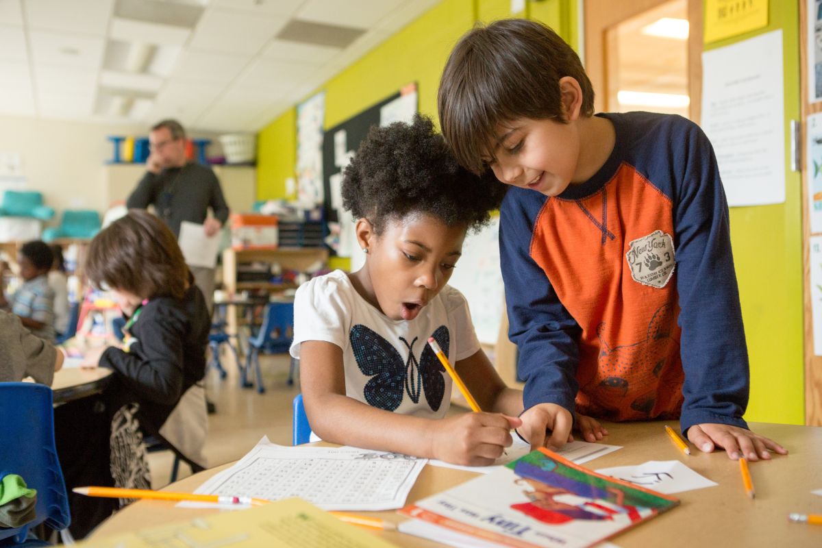 Teacher pointing to a class-made 'Ways we are kind' chart